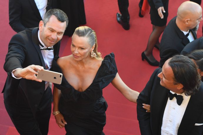 US-Canadian actress Pamela Anderson (C) poses for selfies as she arrives on May 20, 2017 for the screening of the film '120 Beats Per Minute (120 Battements Par Minute)' at the 70th edition of the Cannes Film Festival in Cannes, southern France. / AFP PHOTO / Antonin THUILLIER
